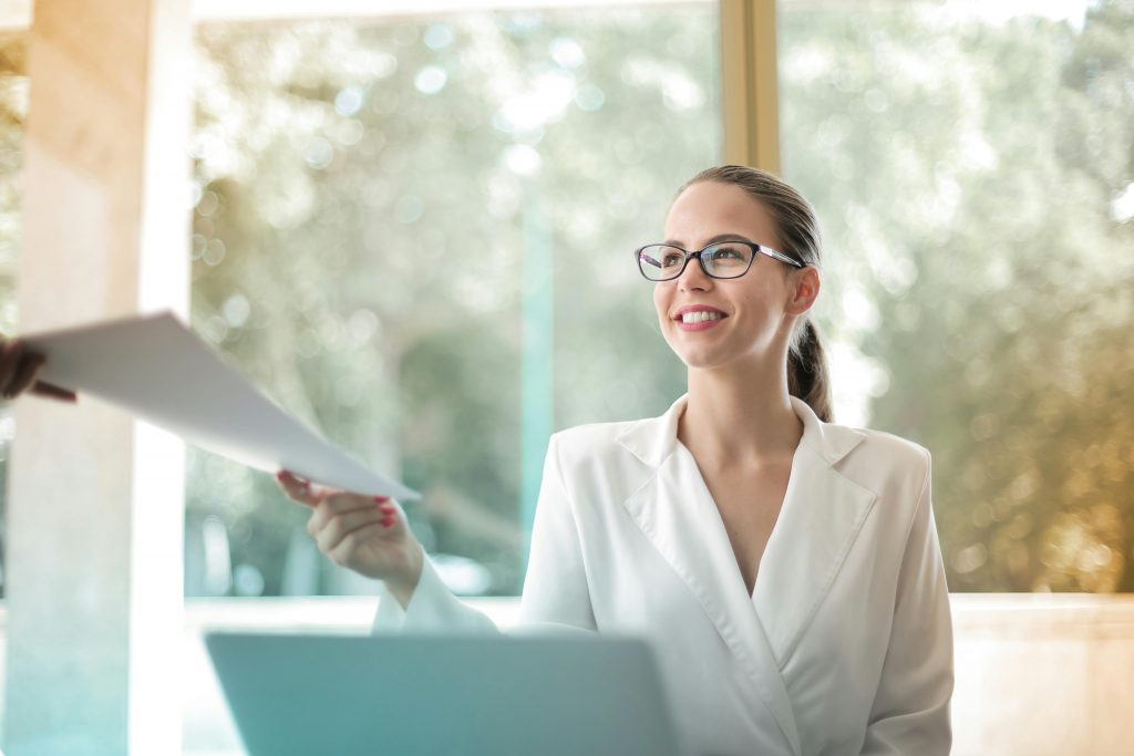 Woman at work hands a document to a colleague